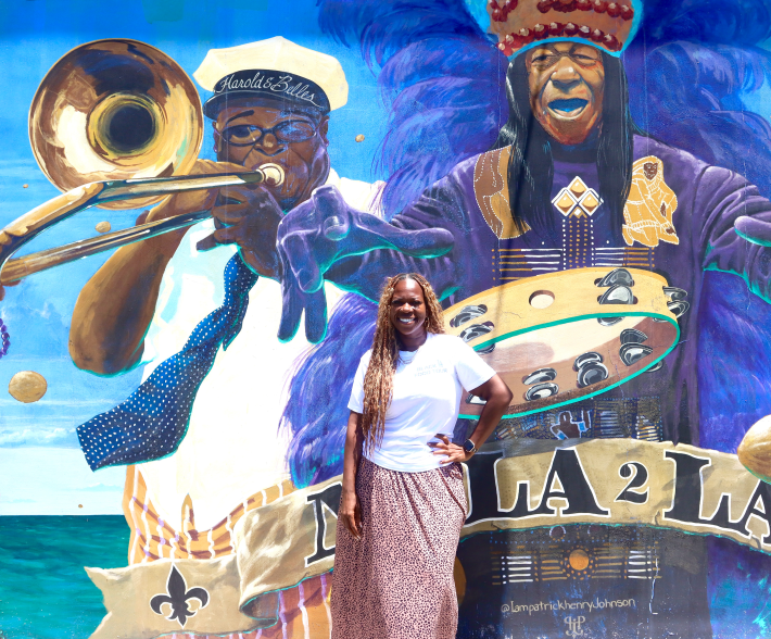 a woman poses in front of a mural