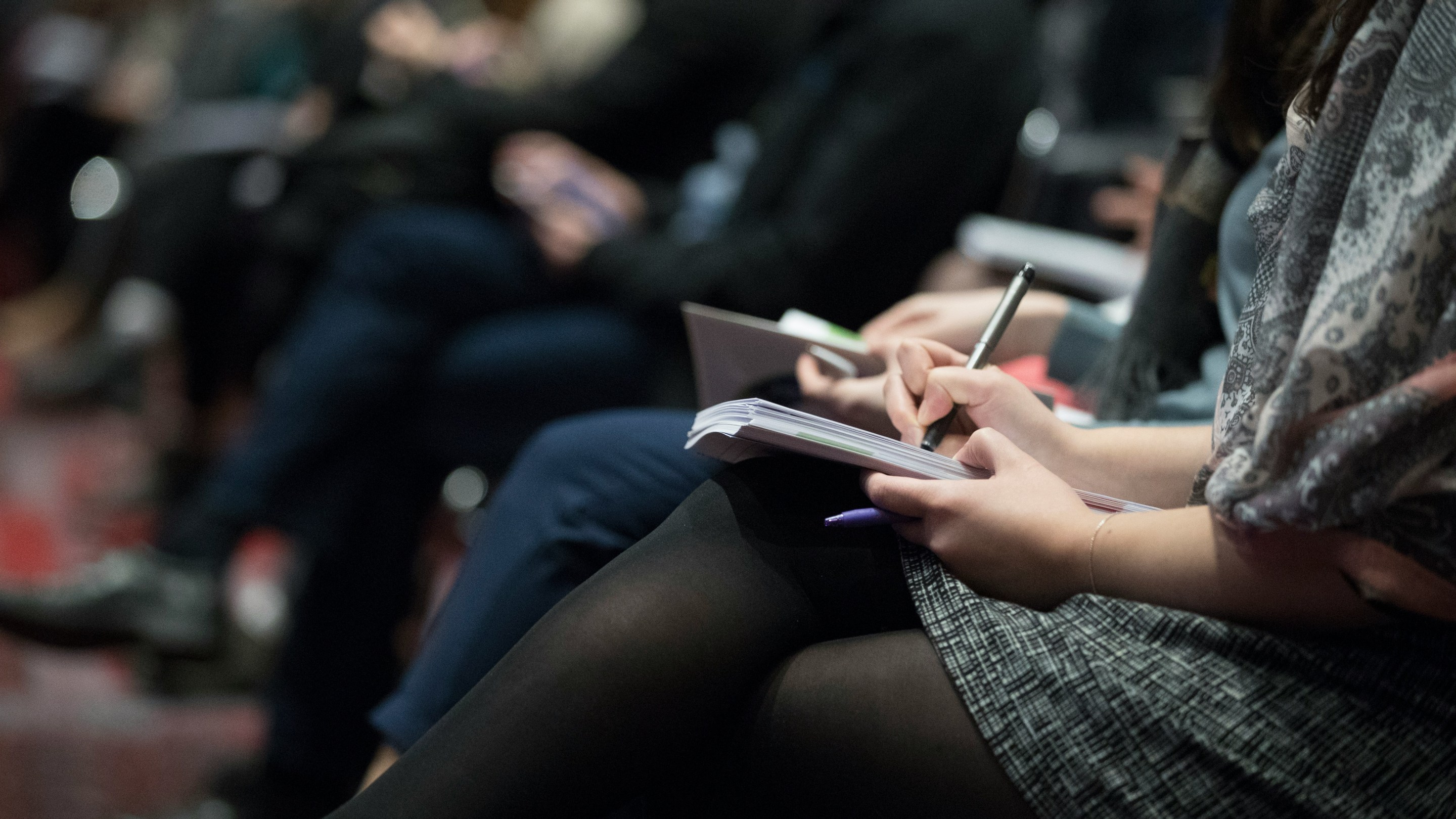A row of reporters knees with hands on their notebooks