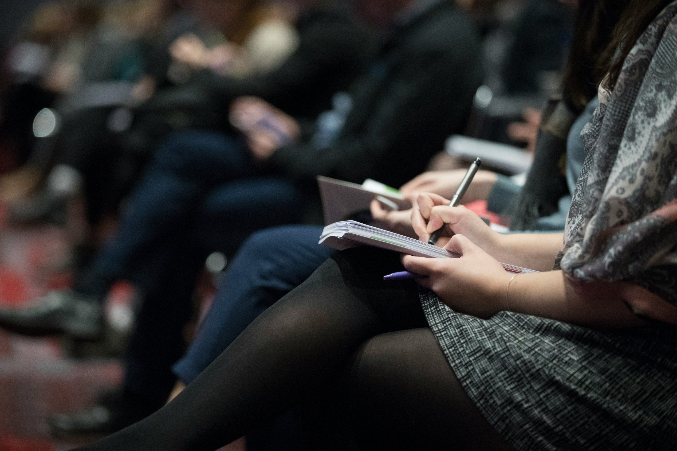 A row of reporters knees with hands on their notebooks