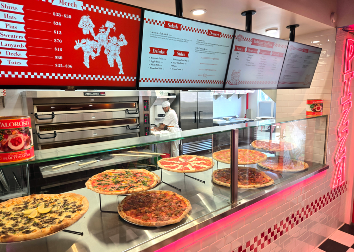 A pizza counter with pizzas and a menu showing an illustration of the Teenage Mutant Ninja Turtles