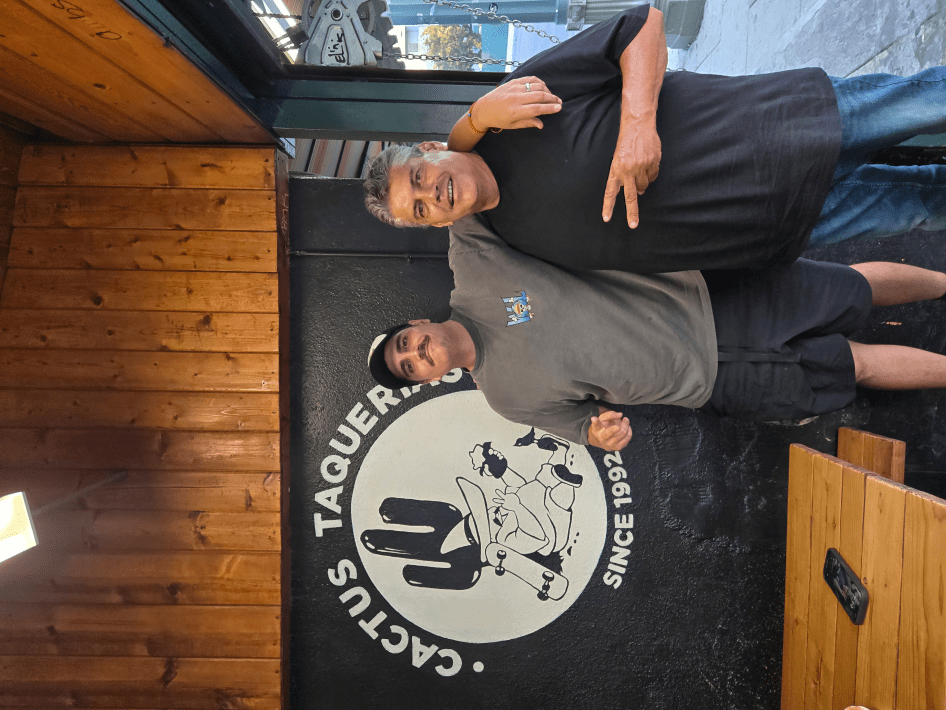 a father and son standing next to their restaurant logo