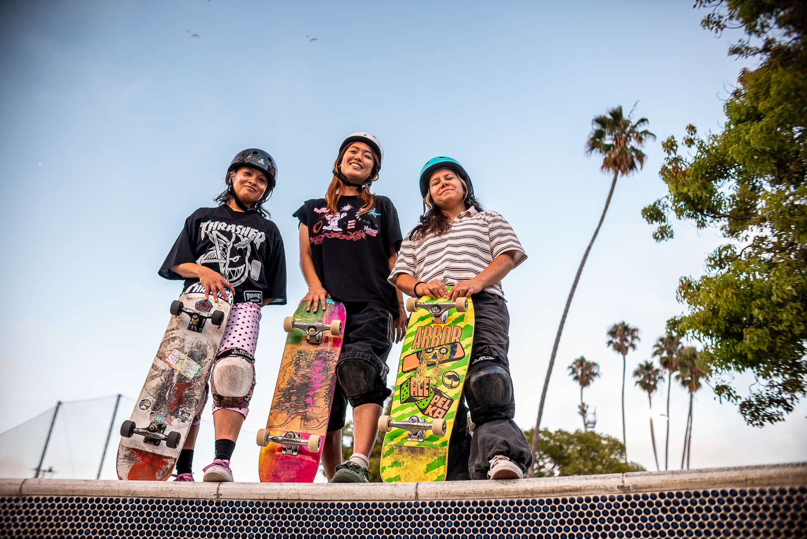 three woman skaters pose together with their skateboards