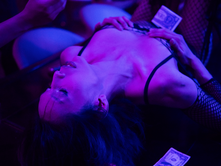 a dancer laying down on stage with dollar bills around her