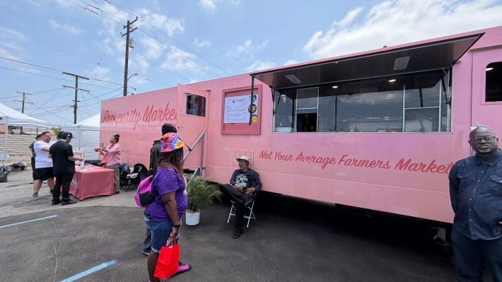 people in front of a pink mobile farmers market