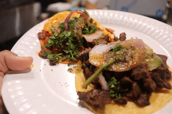 a plate of two tacos, one al pastor and one asada