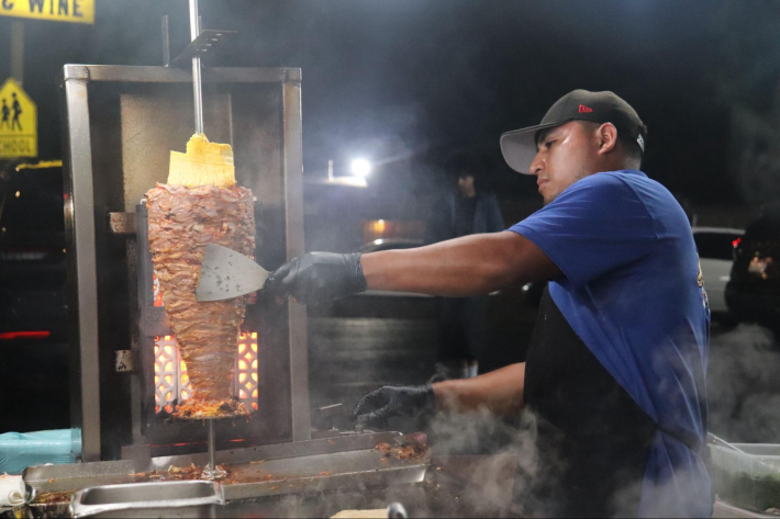 a man working on an al pastor trompo