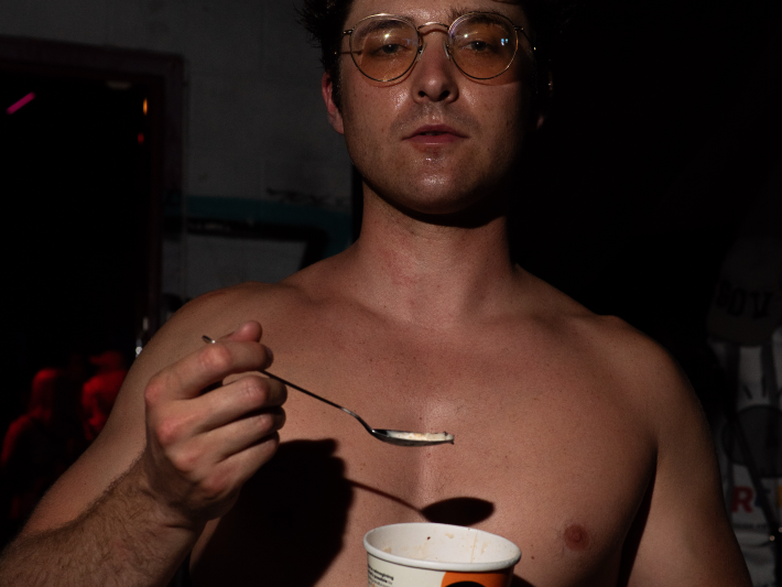 a shirtless man eats ice cream