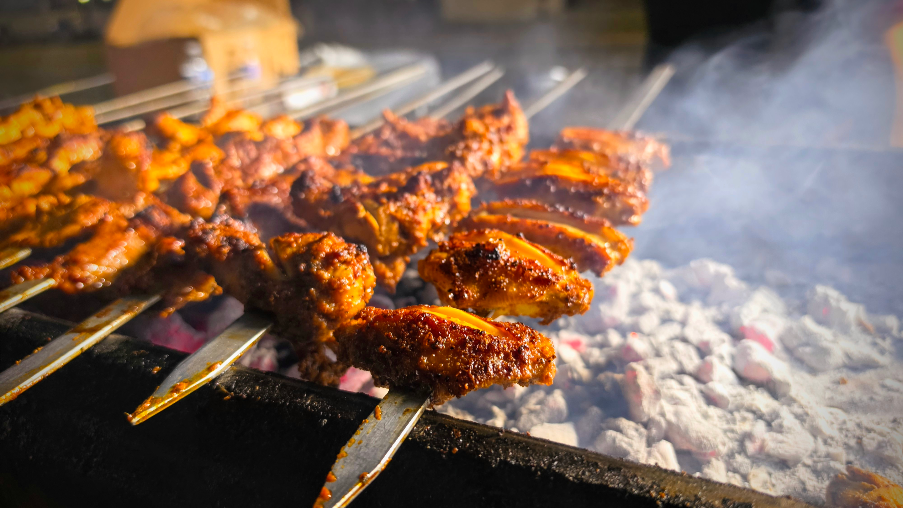 Chicken wing skewers grilled over charcoals
