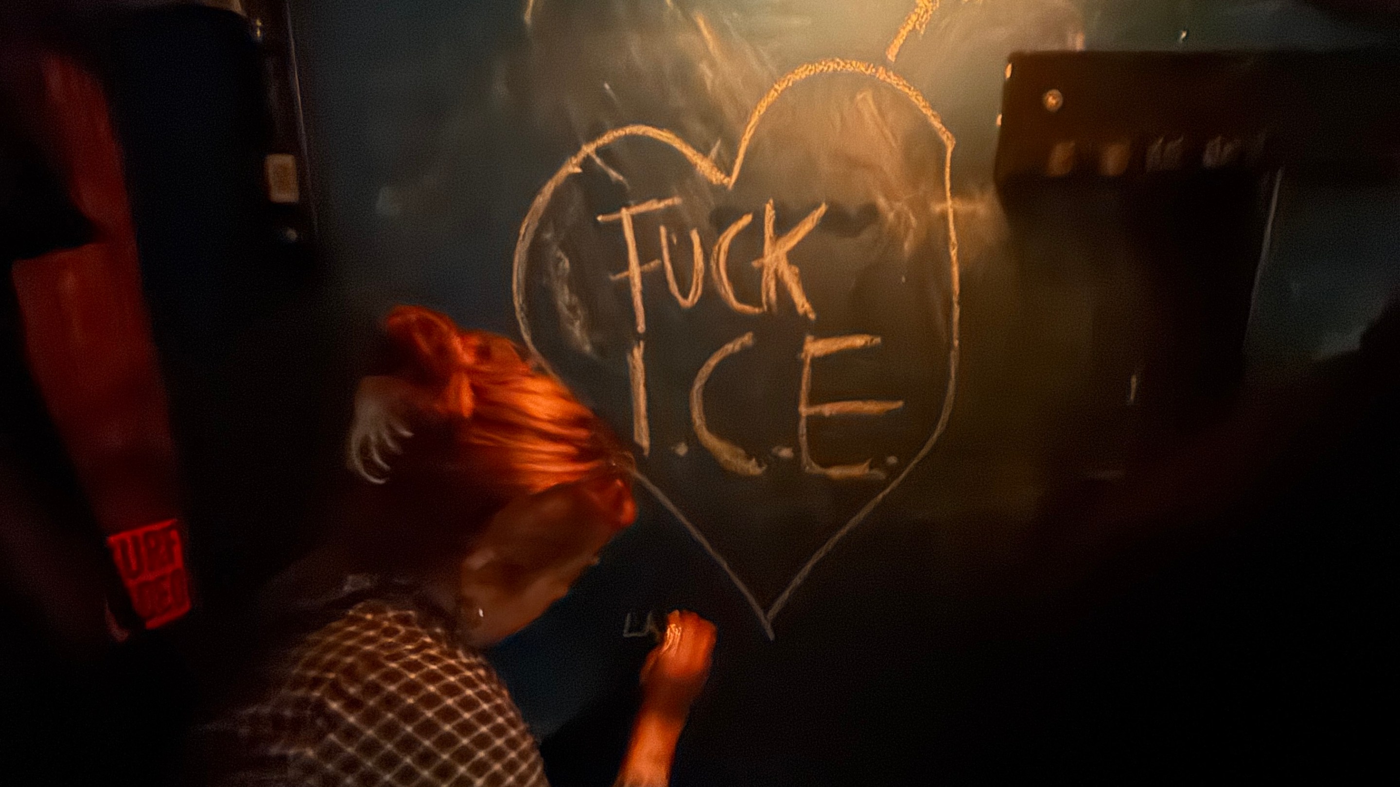 a woman leaves a love note for ICE on a chalkboard