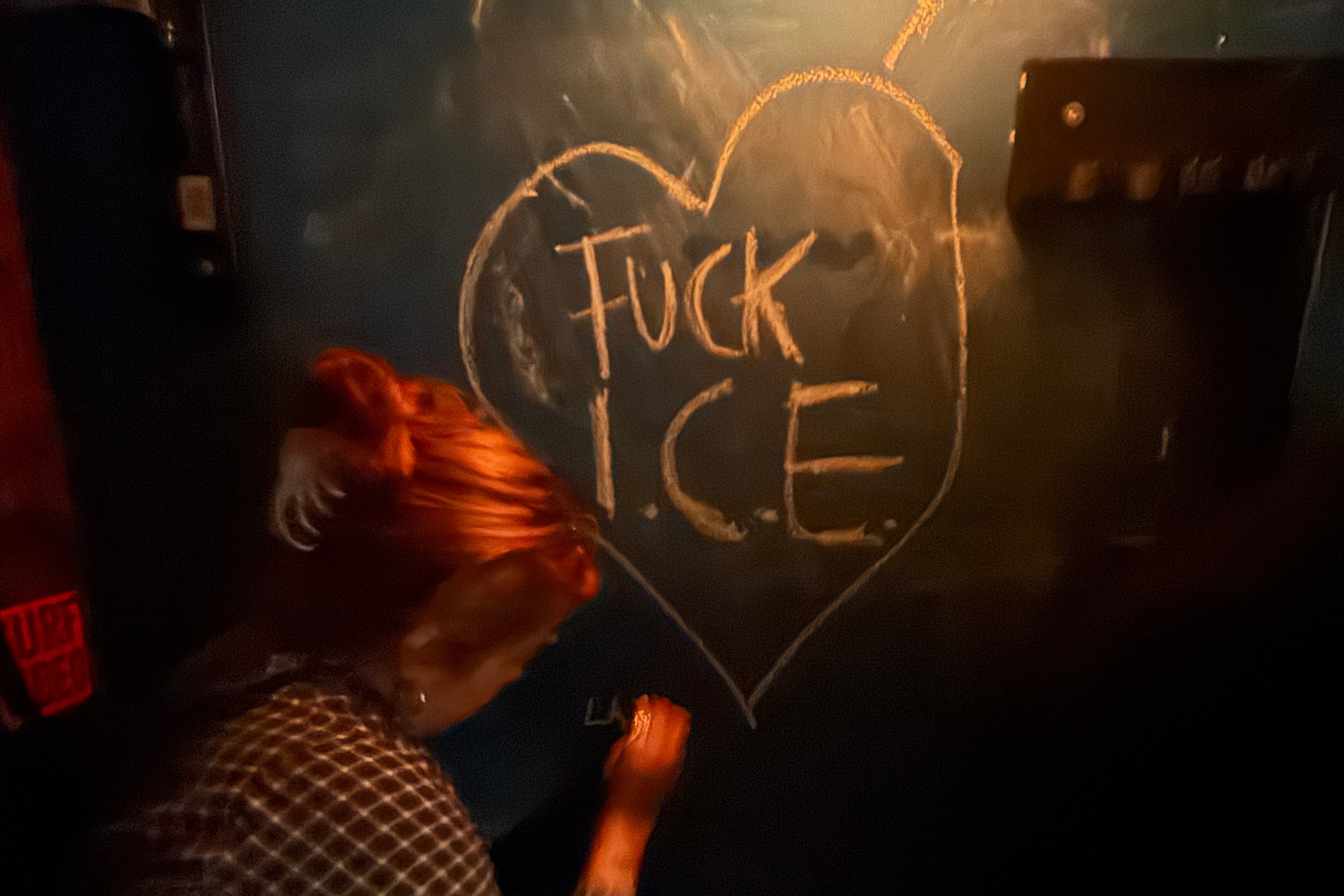 a woman leaves a love note for ICE on a chalkboard