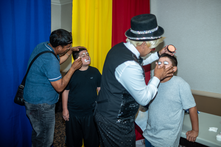 two clowns do clown makeup on kids