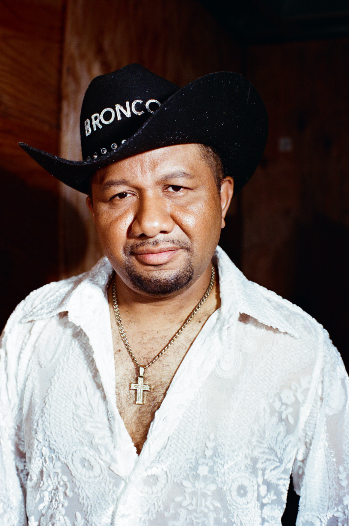 a man with a cross necklace and cowboy hat
