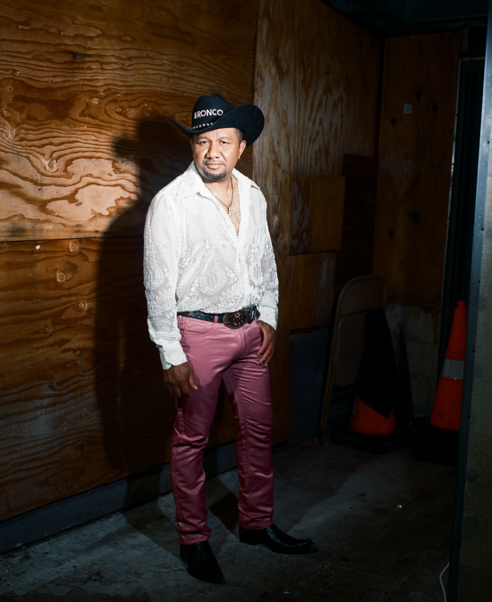 a man with a cross necklace and cowboy hat