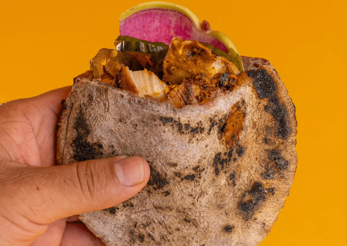 An achiote-and-saffron-marinated chicken in a handheld pita