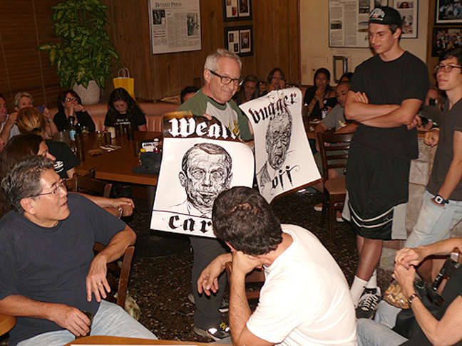 a man holds two posters in a crowd
