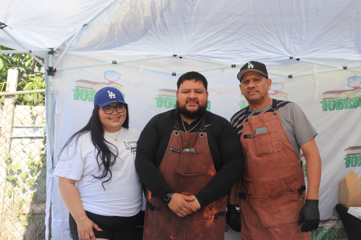 a woman in a Dodgers cap posing with two men in aprons