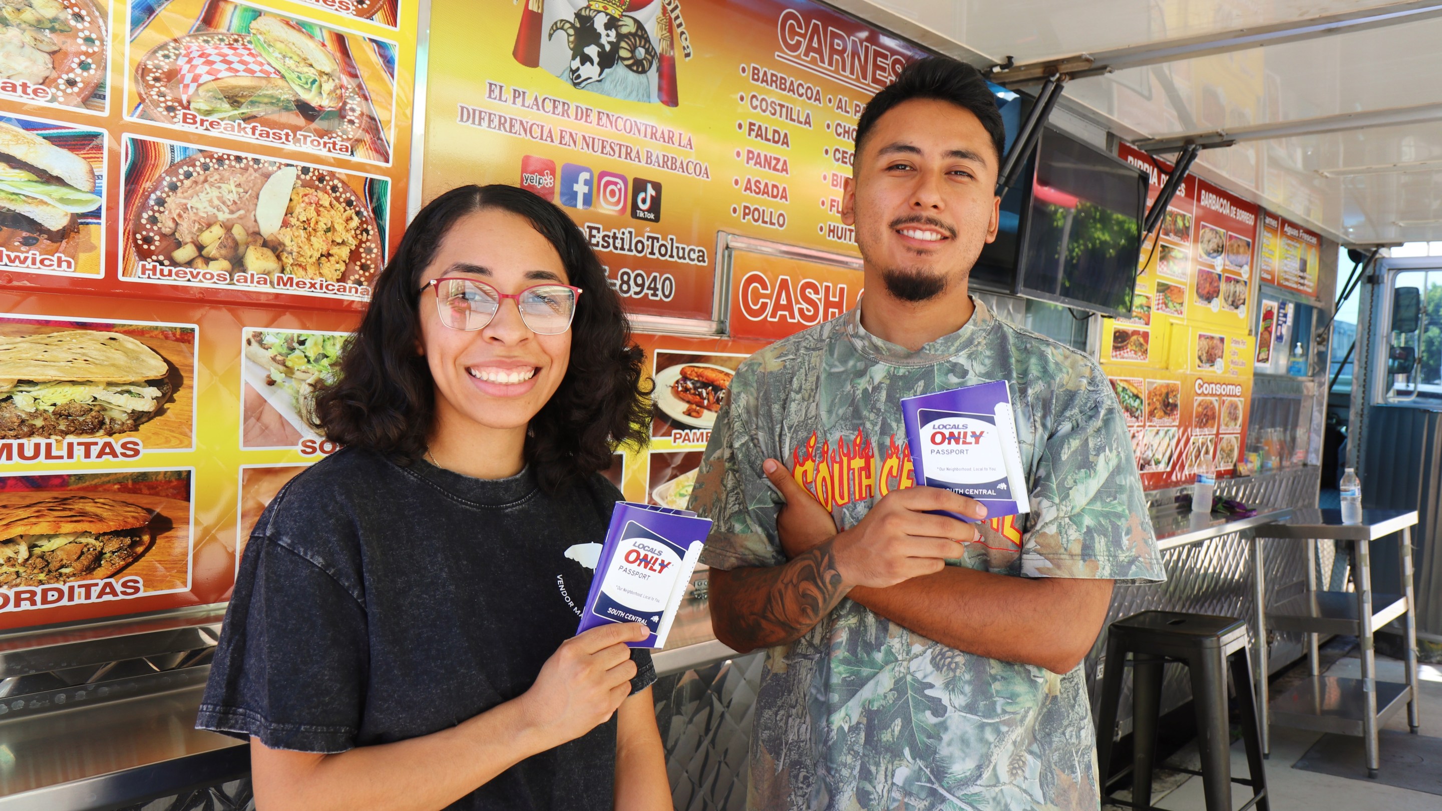 a man and woman hold passports they created outside a food truck