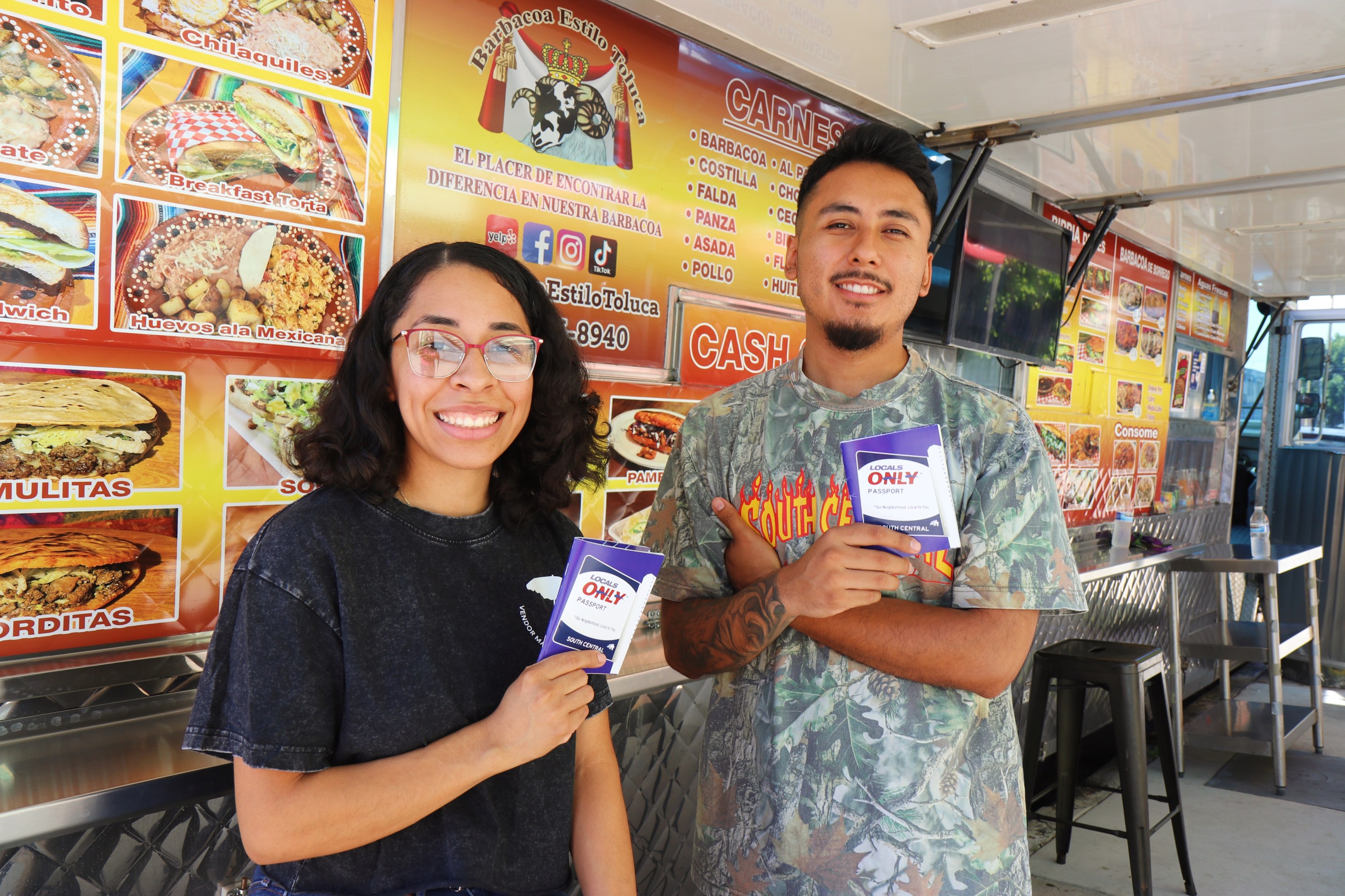 a man and woman hold passports they created outside a food truck