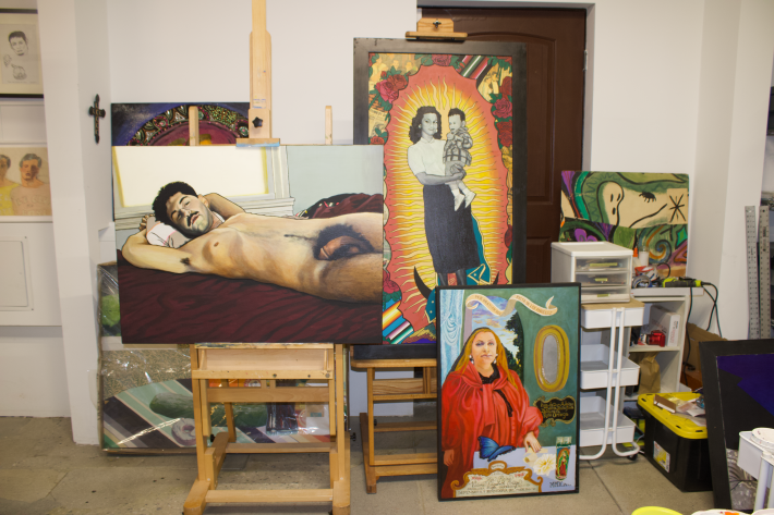 artwork inside a studio: paintings of a nude man, a woman holding a baby, a woman in robes