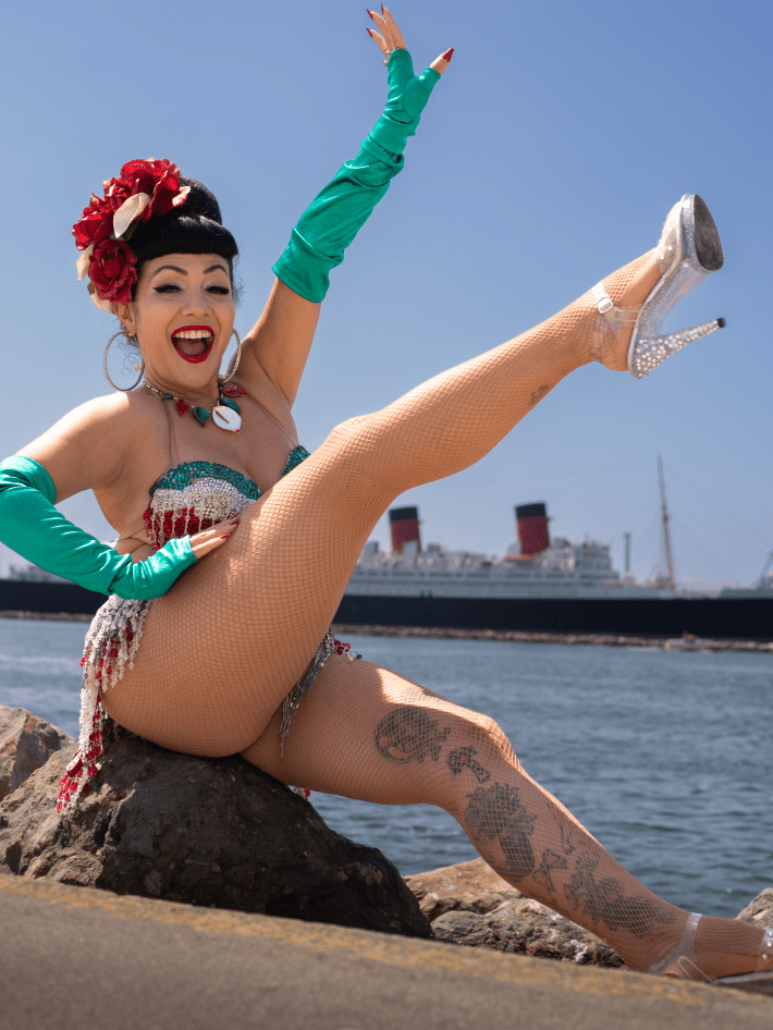 a woman poses on a rock in front of the Queen Mary