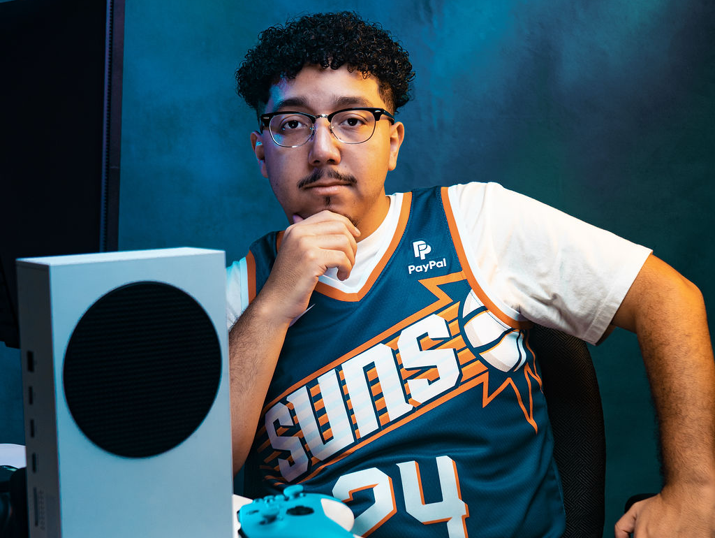 a man in a jersey posing at a desk with a gaming computer