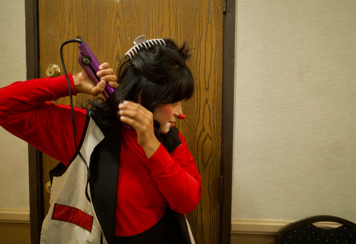 a woman dressed as a clown straightens her hair