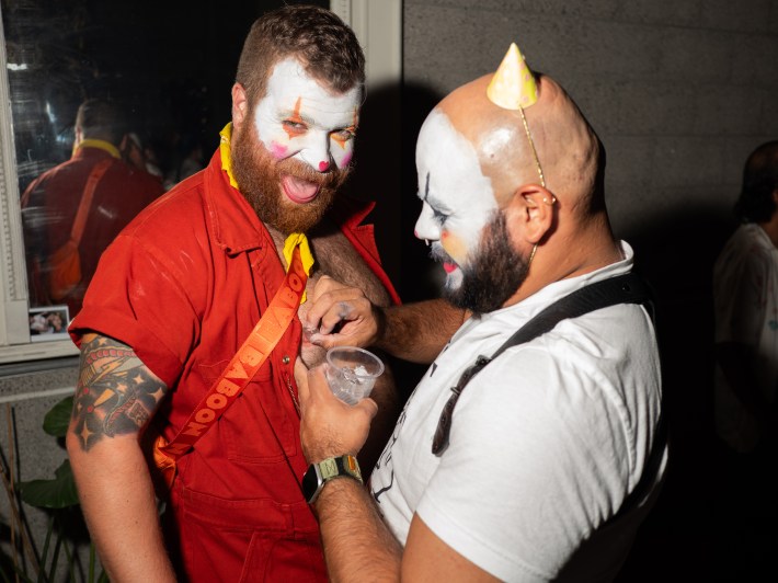 two men at a party, one getting their nipples iced