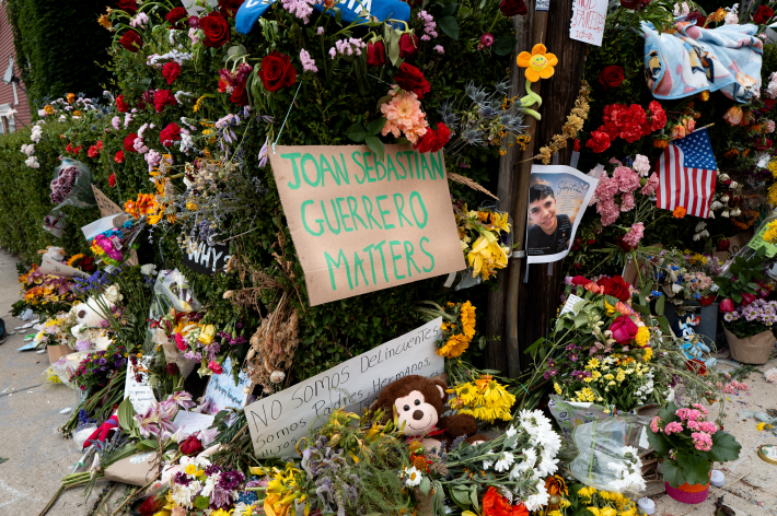 A memorial for Joan Sebastian Guerrero with flowers and signs