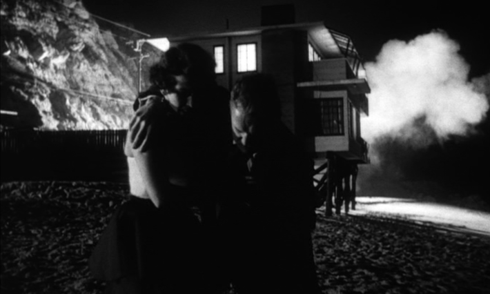 Velda (Maxine Cooper) and Mike (Ralph Meeker) escape from Dr. Soberin's beach house