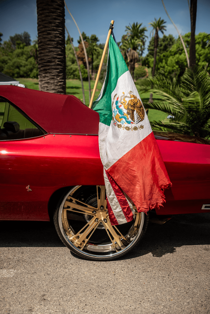 a classic red car with a Mexican flag and American flag