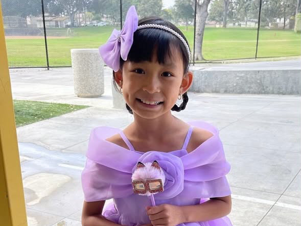 a little girl in a purple headband and dress