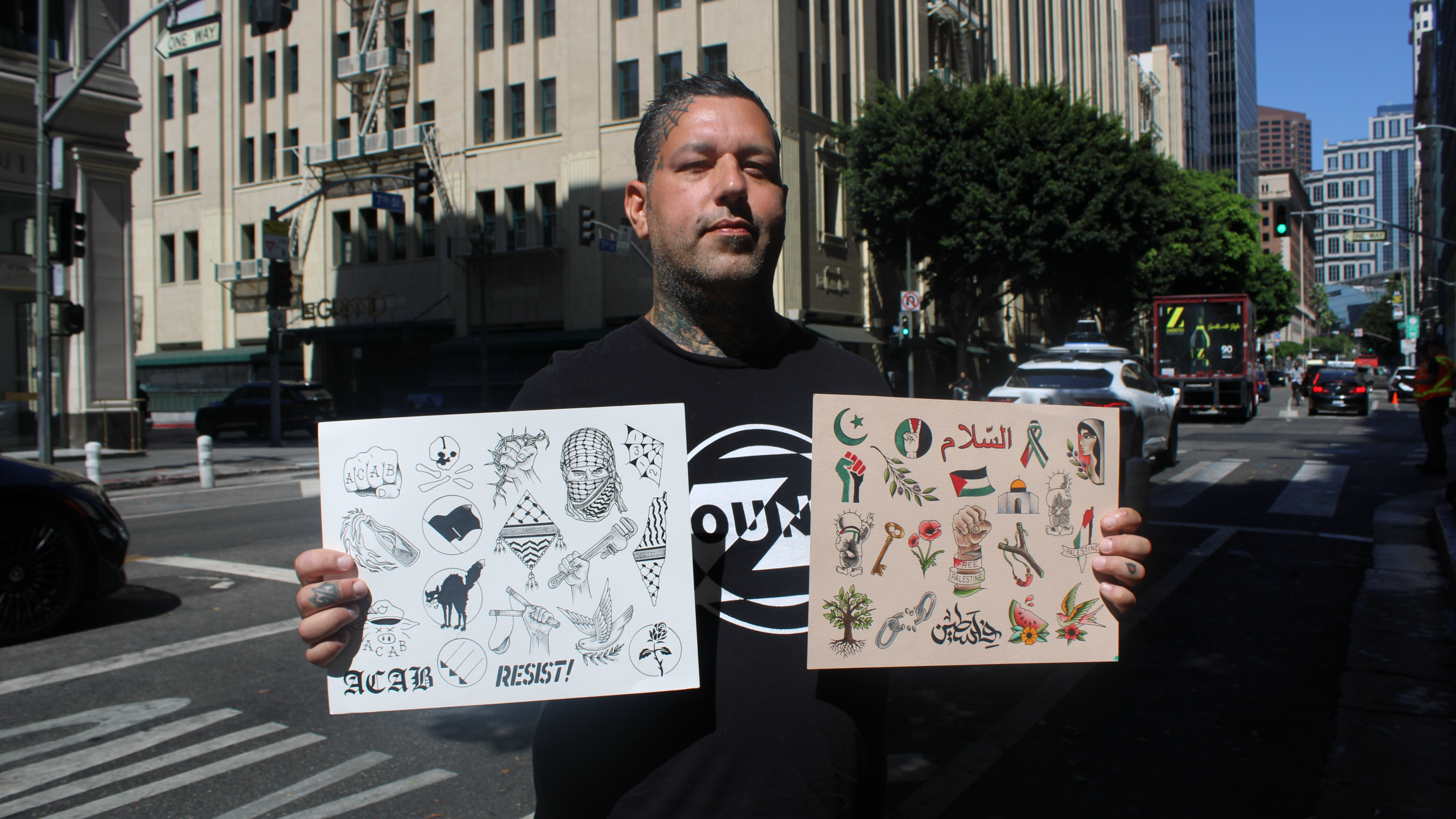 a tattoo artist holds his flash sheets with imagery related to Palestine