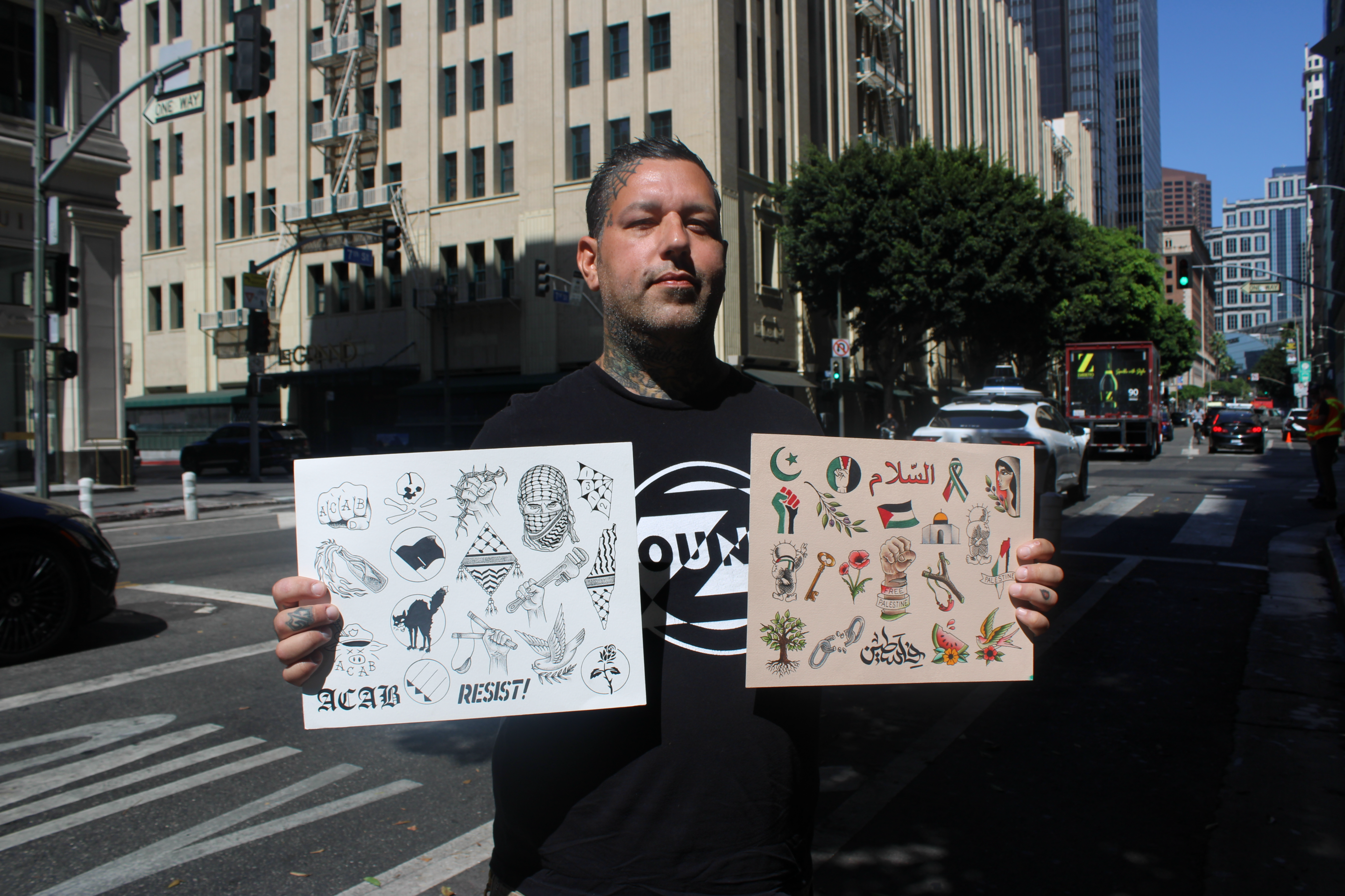 a tattoo artist holds his flash sheets with imagery related to Palestine
