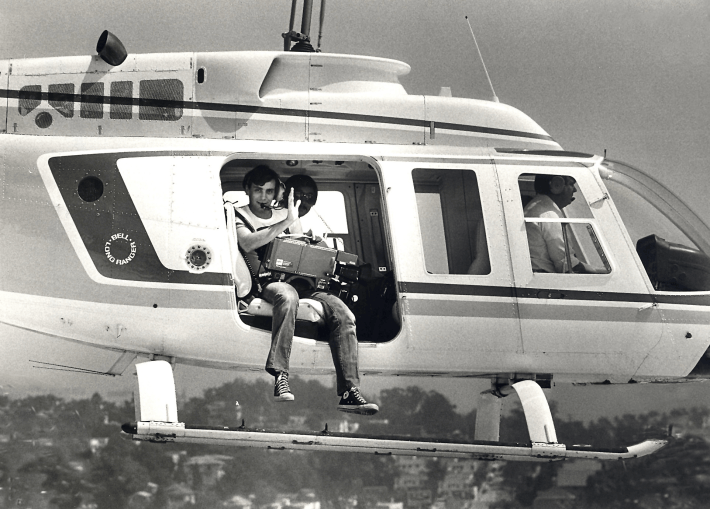 a black and white photo of a young cameraman in a chopper