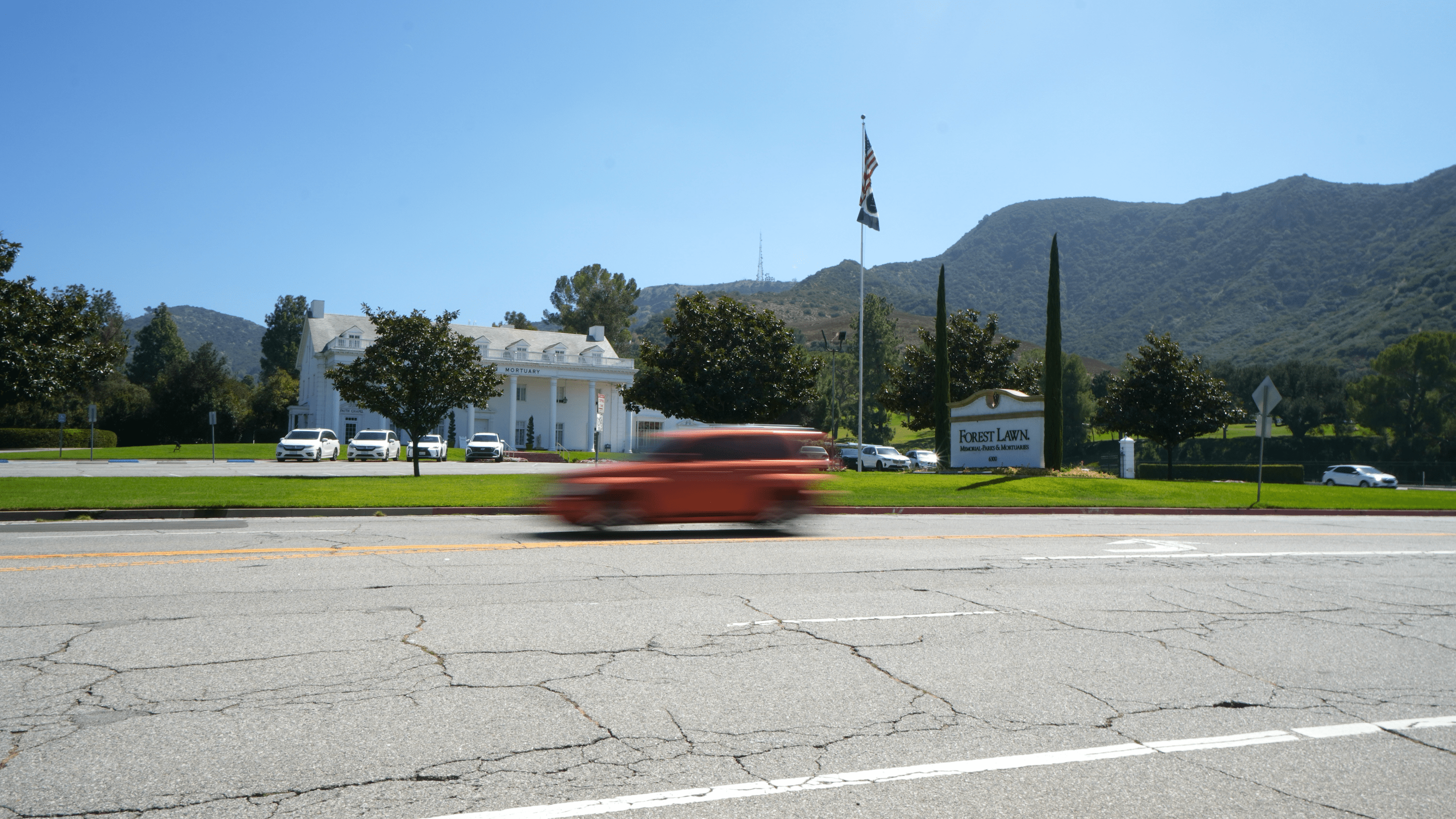 a car driving down a road in front of a cemetery