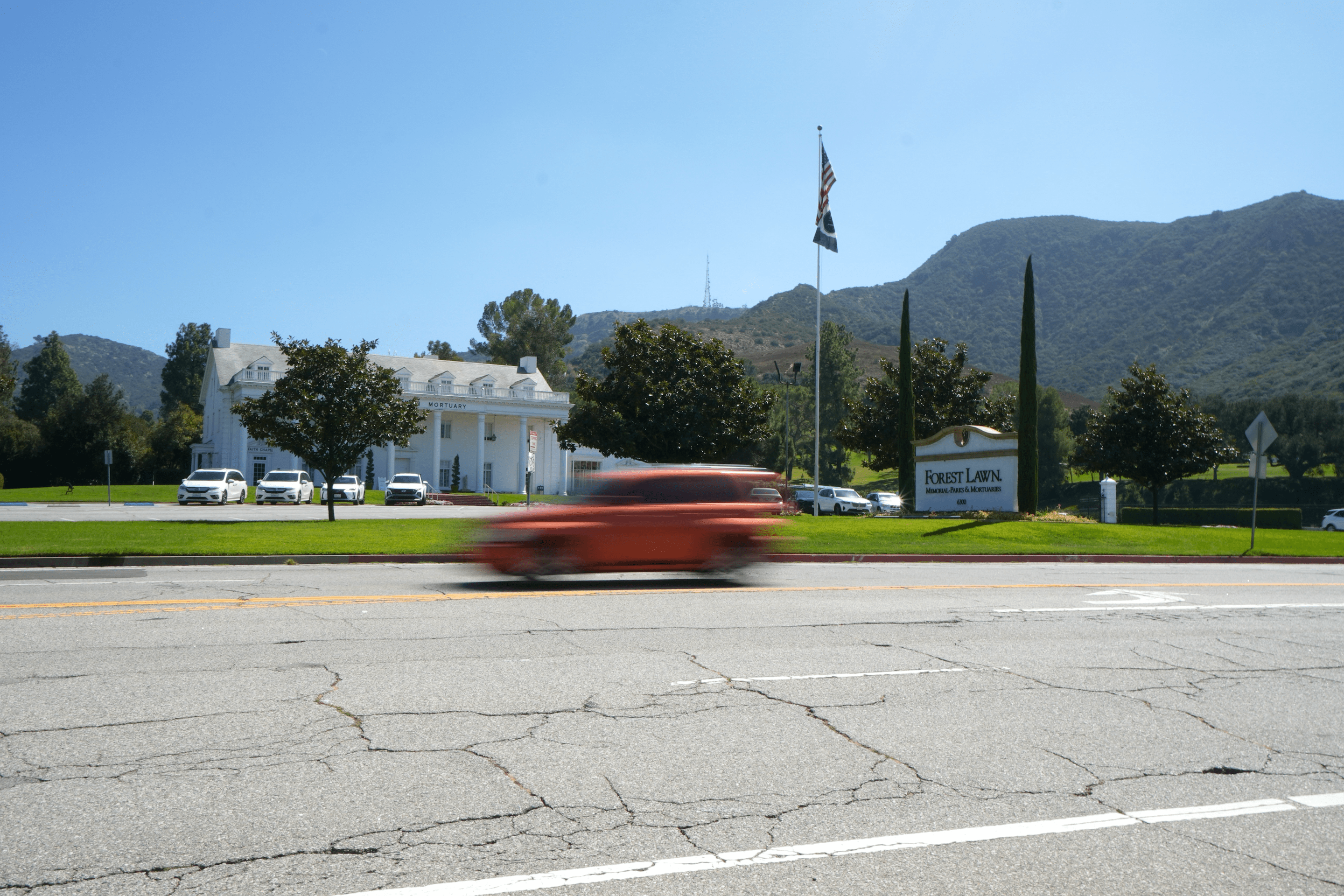 a car driving down a road in front of a cemetery