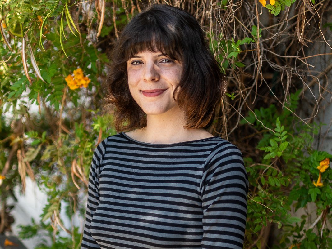 a woman in a striped shirt in front of vines
