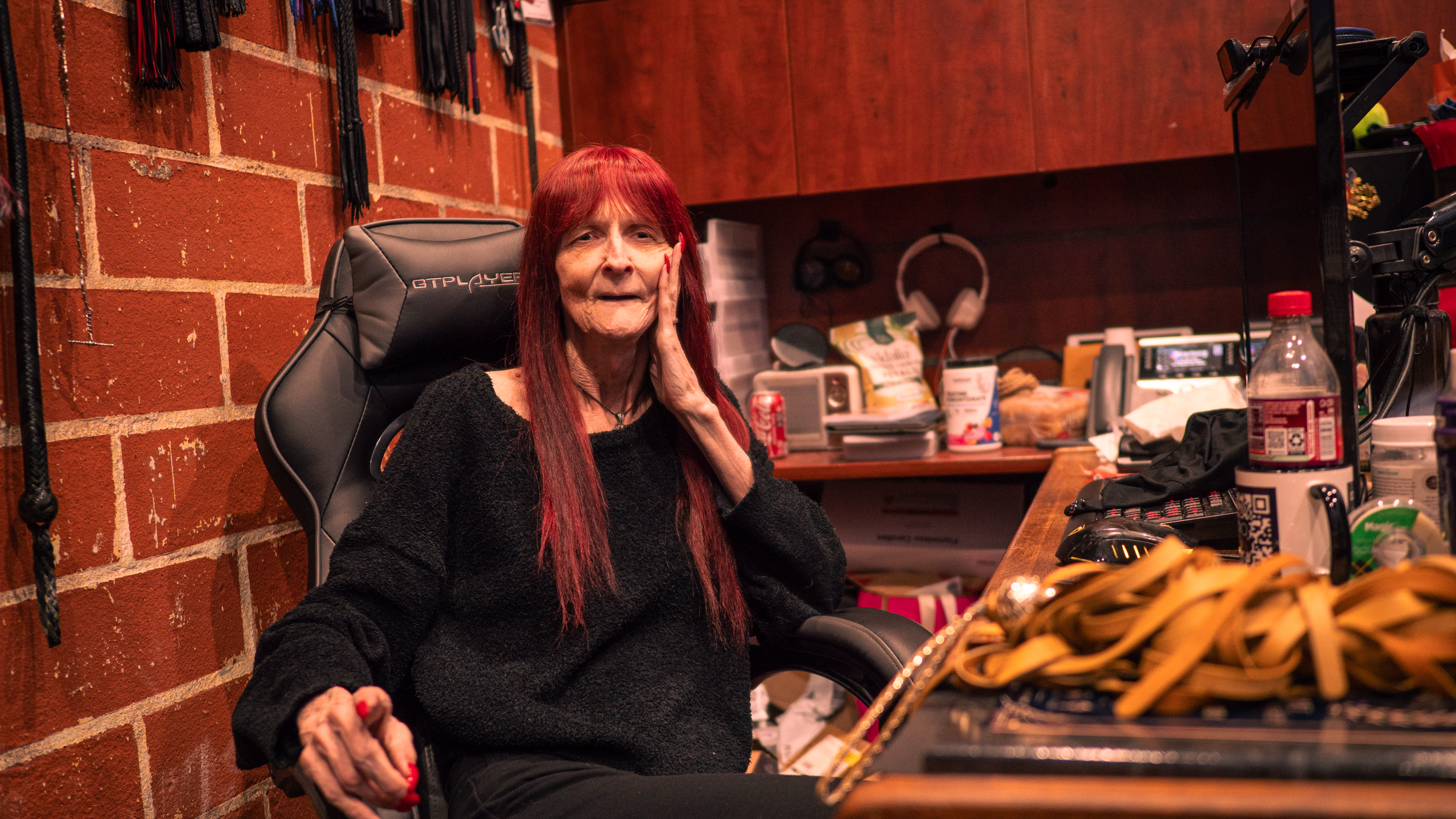 a mistress at her desk next to BDSM materials