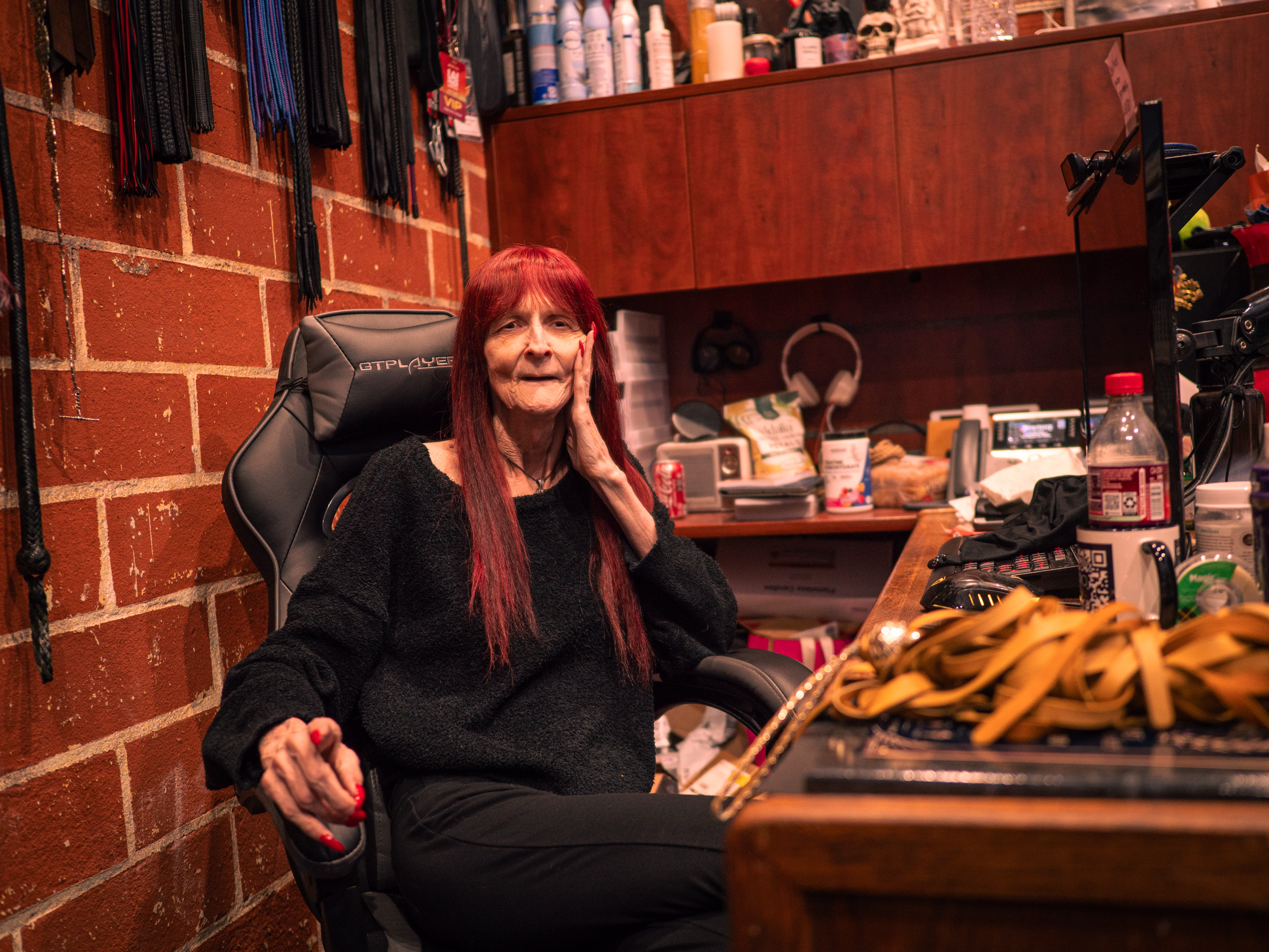 a mistress at her desk next to BDSM materials