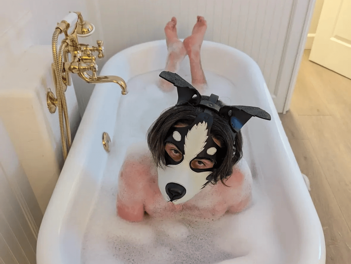 a man in a bubble bath wearing a leather dog mask