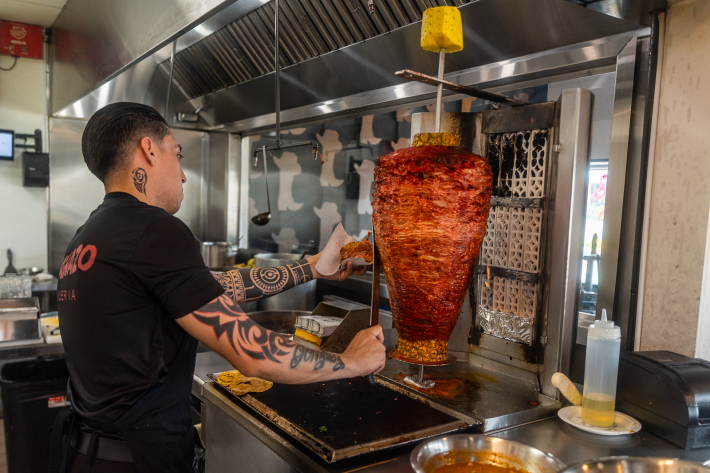 al pastor being sliced from the trompo