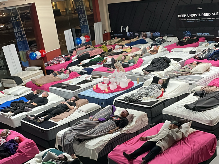 people laying on beds throughout a mattress store