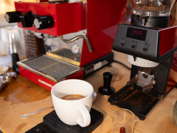 a cup of coffee next to a red espresso machine