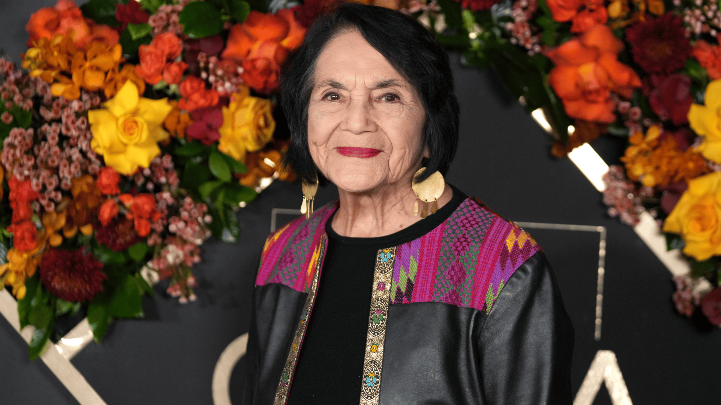 a woman smiles in front of flowers