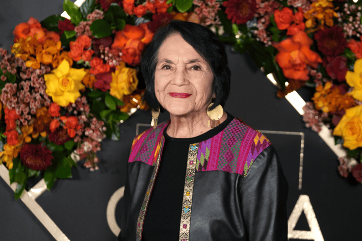 a woman smiles in front of flowers