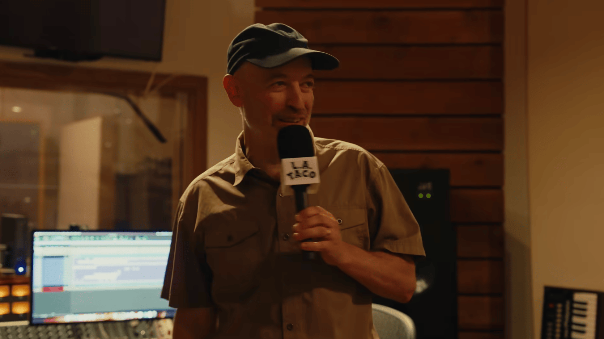 a man in a cap holding a microphone in a recording studio