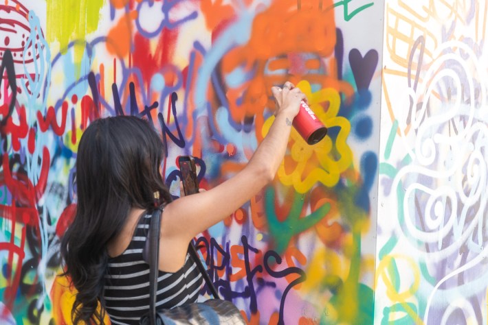 a girl spray paints a wall