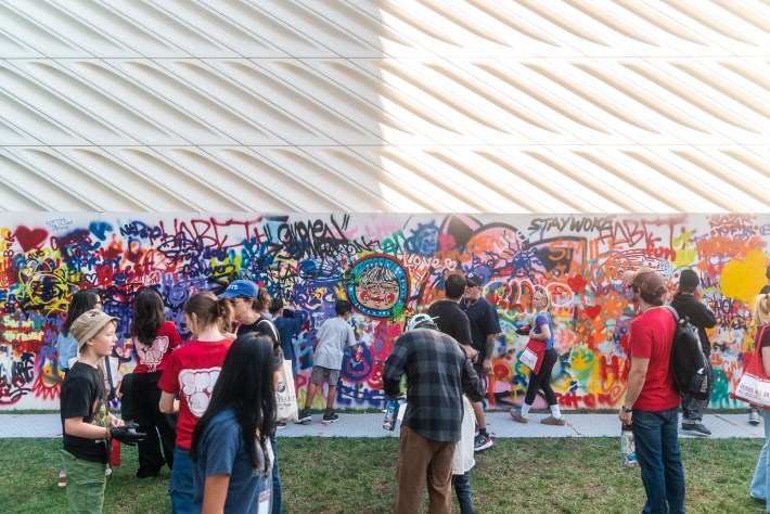adults and kids spray paint a wall