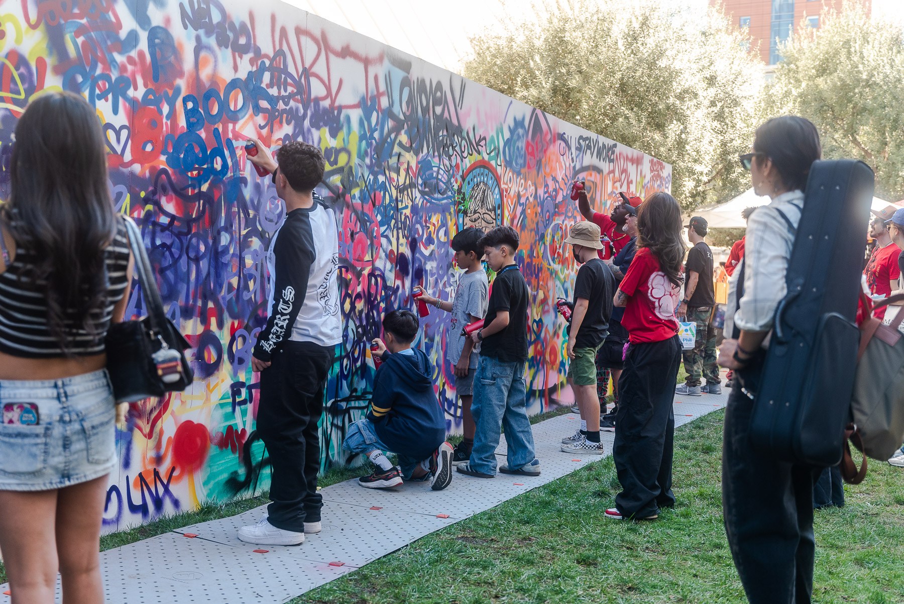 kids and adults spray paint a mural together