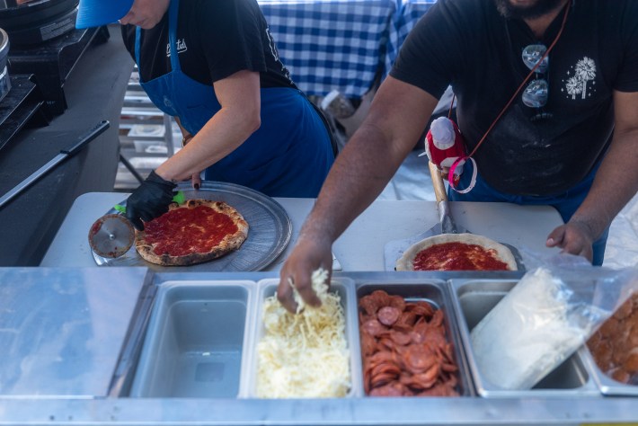 two workers making pizzas